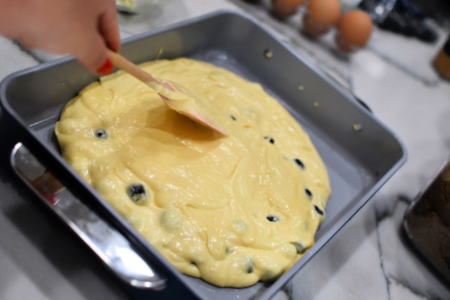 spreading blueberry cake batter into a pan 