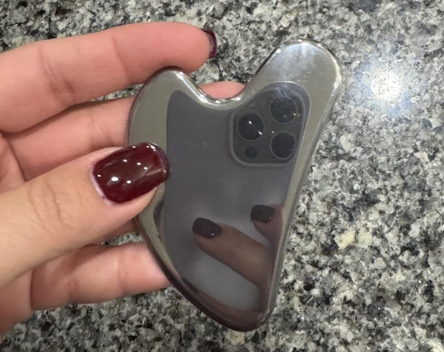 hand holding stainless steel gua sha