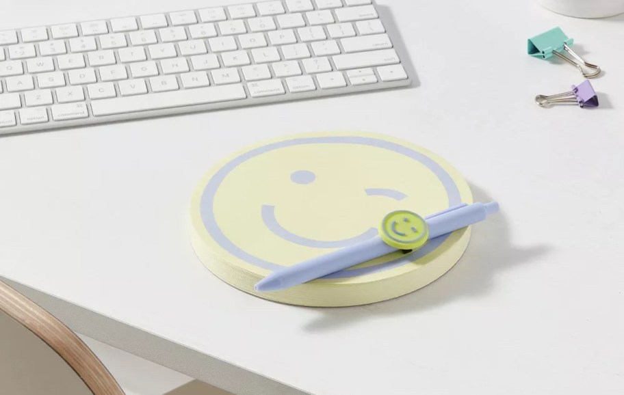 smiley notepad and pen set on computer desk