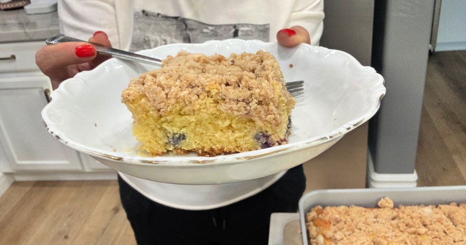 woman holding a plate with blueberry crumb cake 