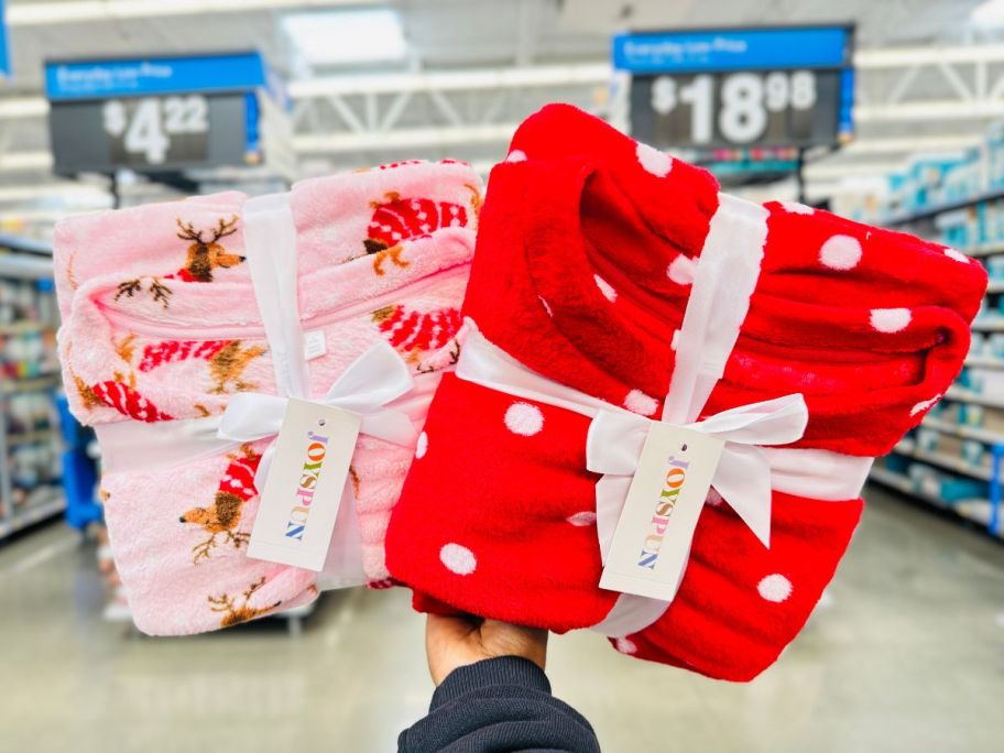 a womans hand holding two sets of womens plush pajamas