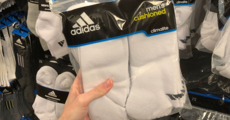 Hand holding a 6-pack of adidas no-showwsocks for men