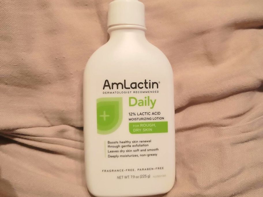 A AmLactin Moisturizing Lotion Bottle on a bed