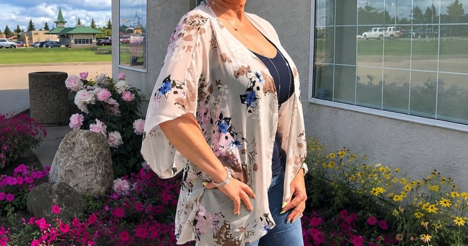 a woman wearing a floral chiffon kimono standing outside a house
