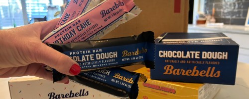 person holding up birthday cake and chocolate dough barebells protein bars