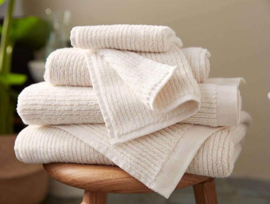 pile of ribbed cream towels on stool in bathroom