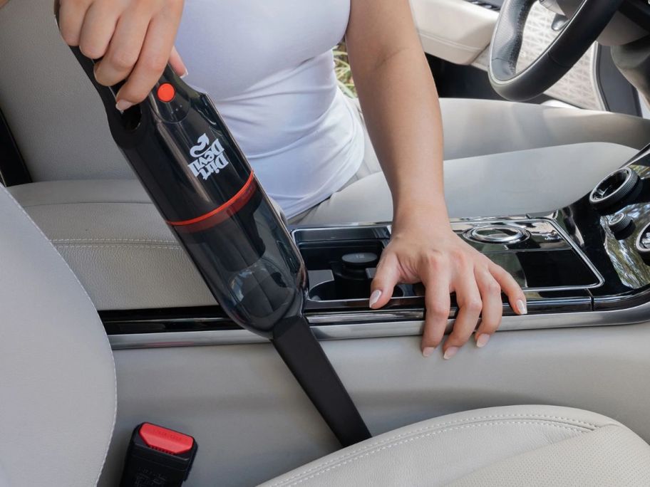 A dirt Devil Hand Vac being using to clean between car seats
