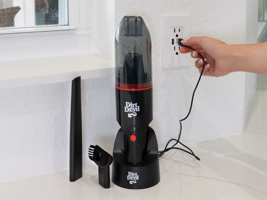 A dirt devil hand vac with two attachments and a charging stand