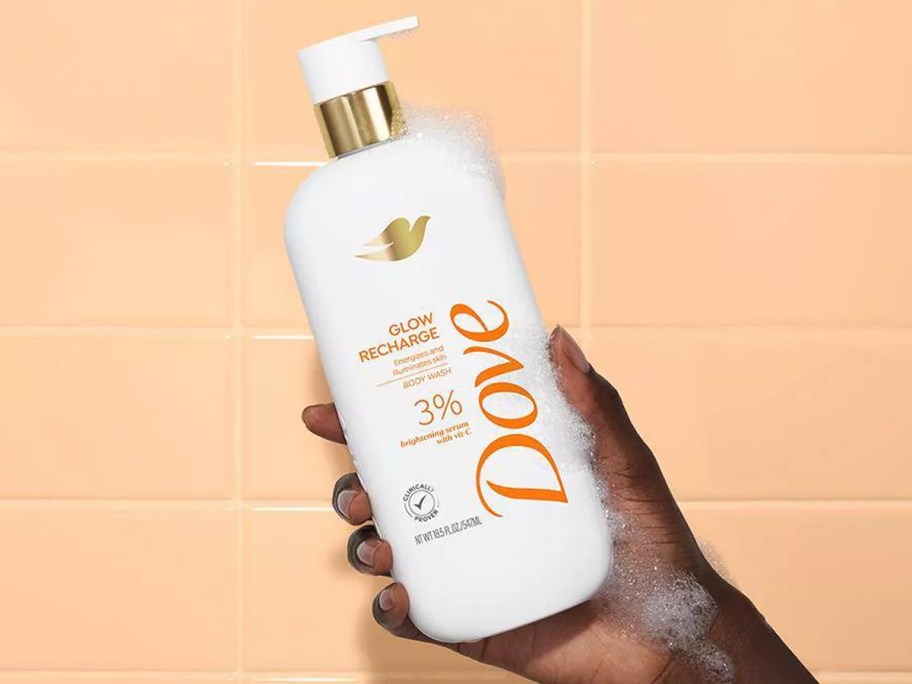 woman holding up a bottle of Dove Glow Recharge Body Wash