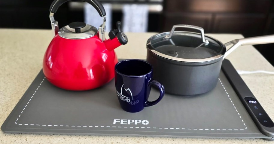 kettle, pot, and coffee mug on top of grey warming mat