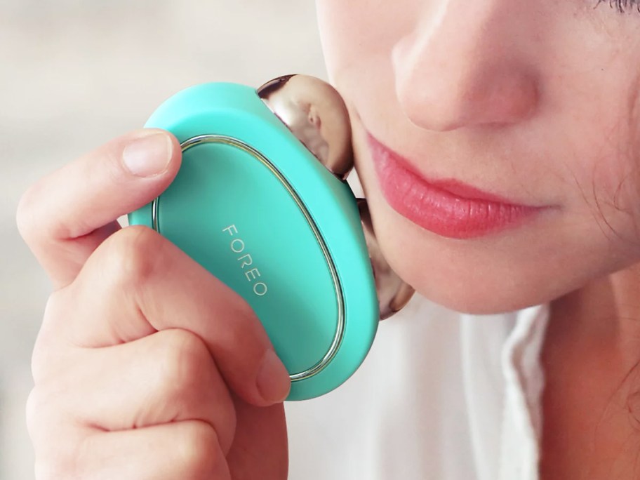 woman using teal FOREO Bear device on her face