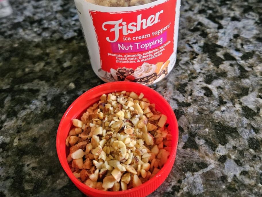 A jar of Fisher Ice Cream Topper with a red bowl of topping set next to it