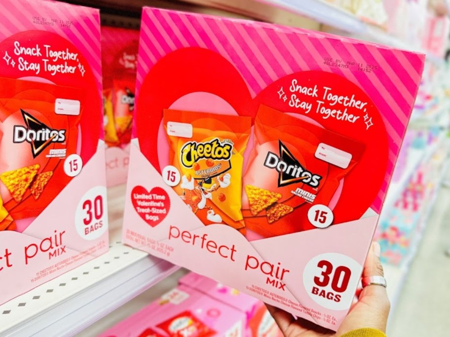 hand pulling a pink box of Cheetos and Doritos Valentine themed chips from a store shelf