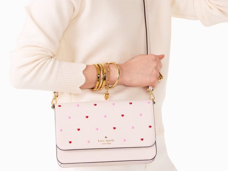 woman in a white sweater with a heart print crossbody bag