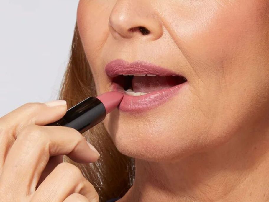 Woman applying Laura Geller's modern classic matte lipstick