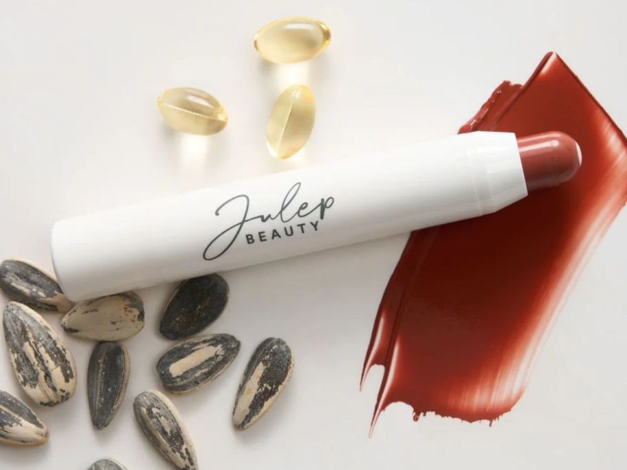 swatched Laura Geller x Julep Lip Crayons next to sunflower seeds and vitamin E capsules