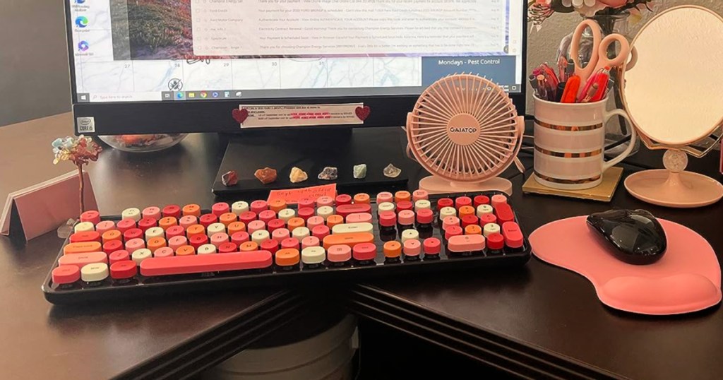 Pink retro keyboard on desk in front of desktop computer