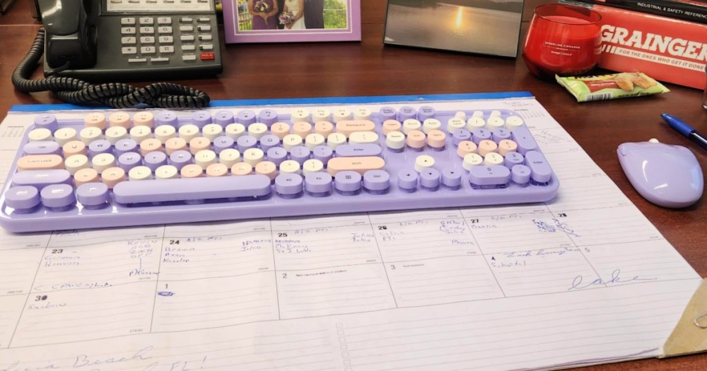 Purple retro keyboard on top of desk, calendar, and in front of telephone