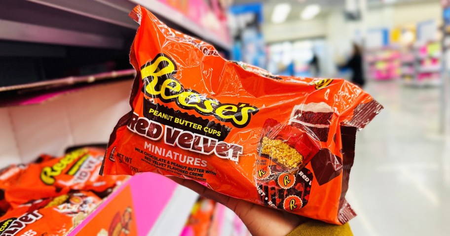 hand holding an orange bag of Reese's Red Velvet Miniature Peanut Butter Cups in store