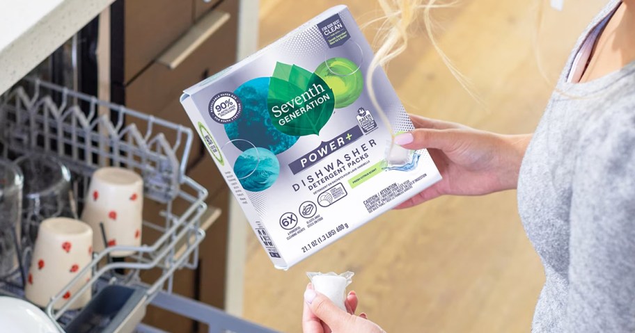 woman holding a box of Seventh Generation Dishwasher Detergent Packs near a dishwasher