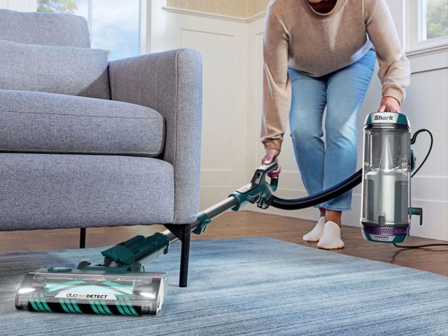 Woman cleaning under a couch using a Shark PowerClean vacuum