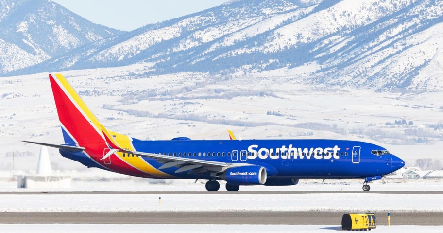 Southwest Airlines plane on runway with snowy mountains in background