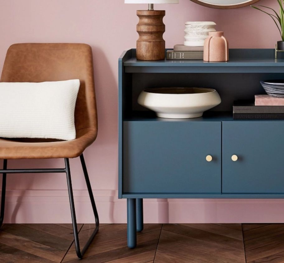 a brown faux leather dining chair next to a blue 2 door cabinet