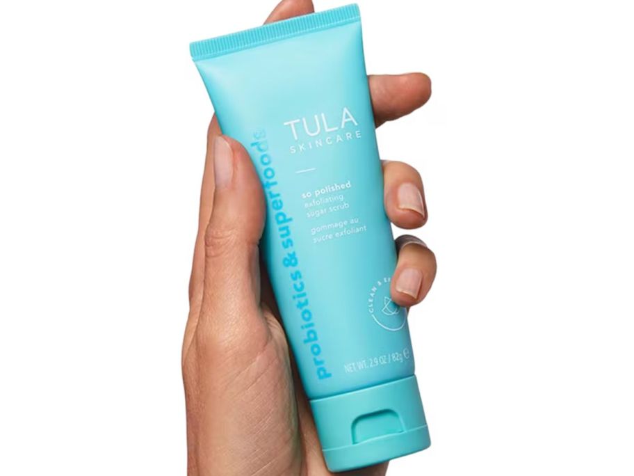 Hand holding a tube of Tula So Polished Sugar Scrub