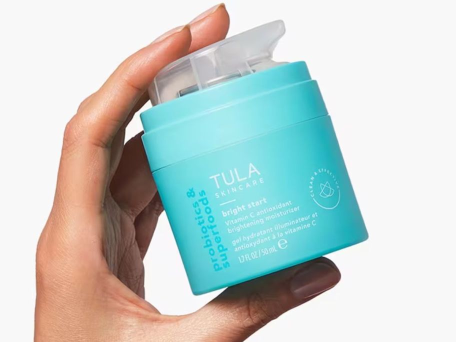 Hand holding a jar of Tula Bright Start Moisturizer