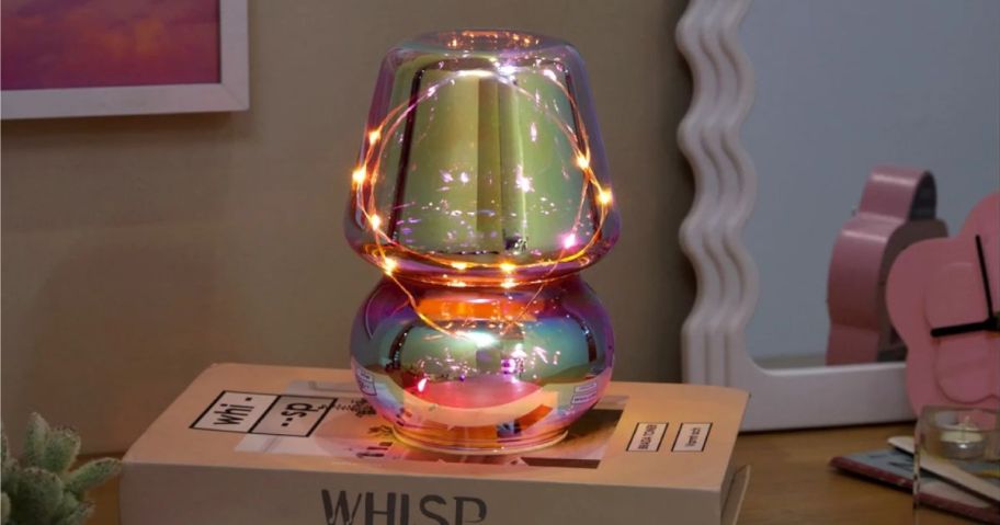 An Iridescent Mushroom Lamp in a dim room on stack of books