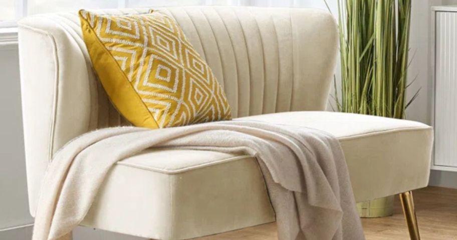 A Wayfair loveseat with a throw blanket and pillow on it