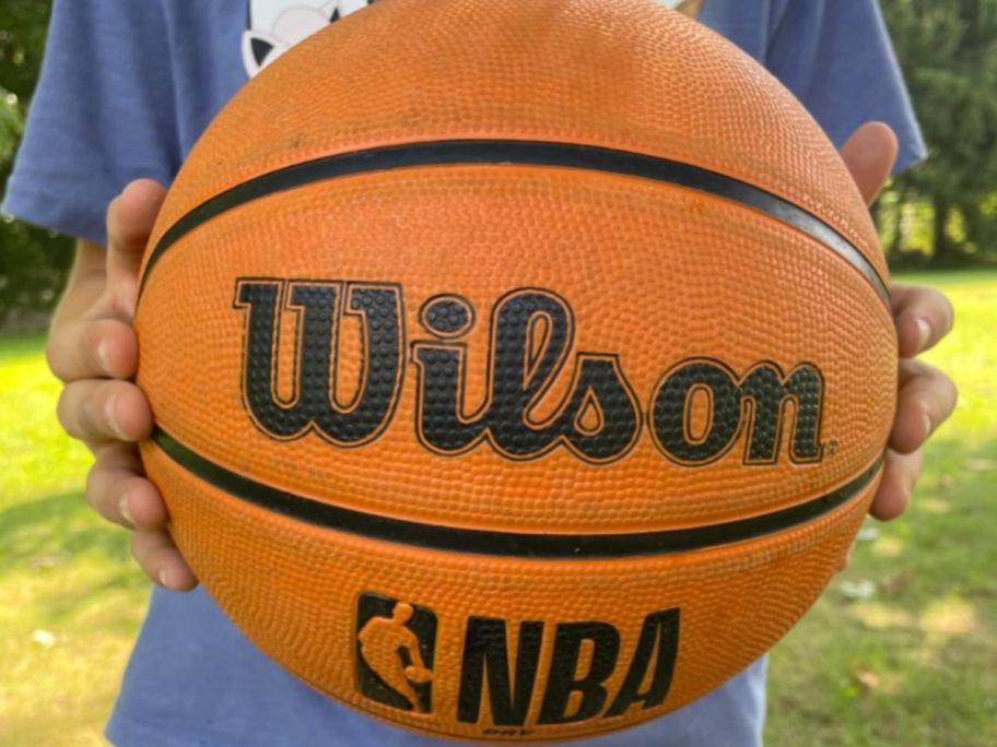 Hands holding a wilson size 5 basketball