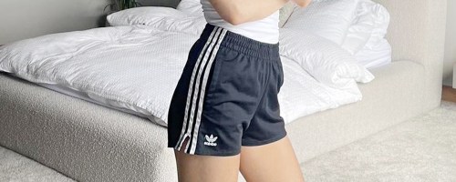 woman wearing black and white adidas shorts in bedroom