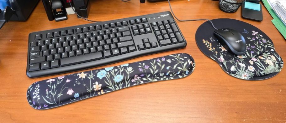 close up of floral mouse and wrist pad for keyboard on wood desk
