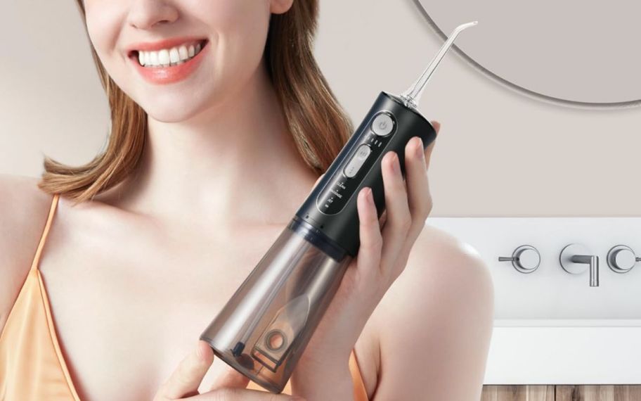 a woman holding a water flosser and smiling