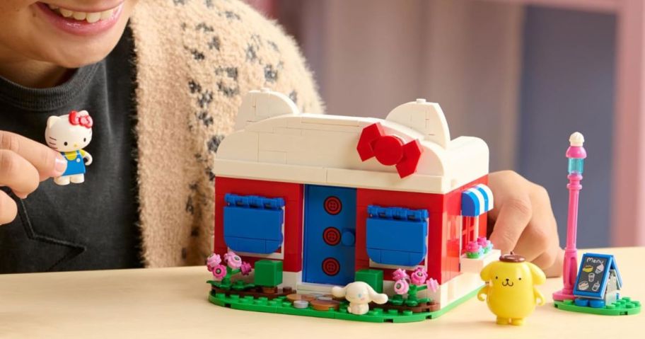 kid playing with BLDR Hello Kitty's Dream Cafe Building Set on table