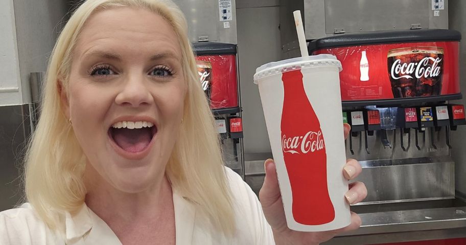 woman holding coca cola cup in front of coca cola soda fountain in store