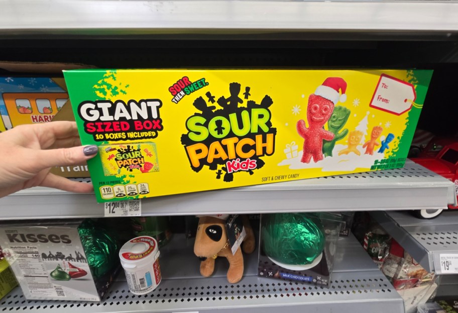 A hand holding a giant box of Sour Patch Kids candy.