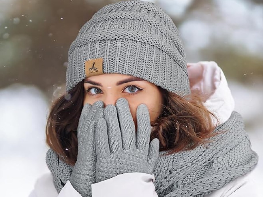 A woman wearing a winter hat, gloves and scart set.