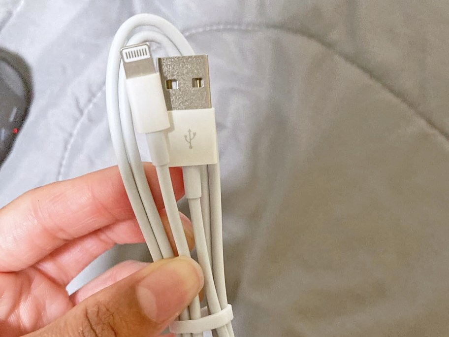 hand holding up a white iphone charging cable