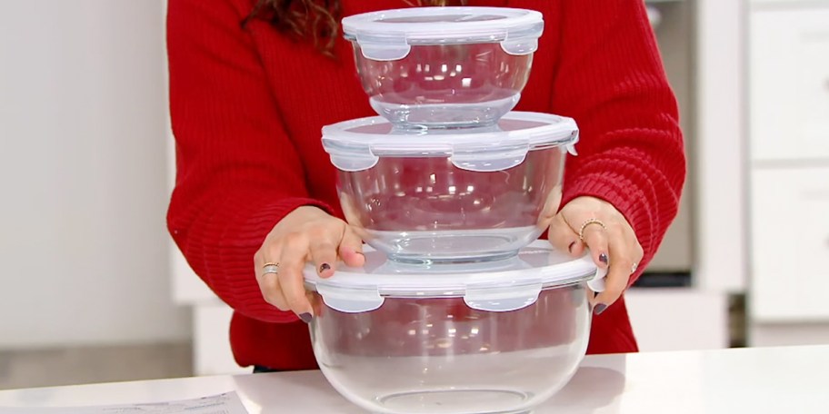 woman holding three glass bowls with white lids on table