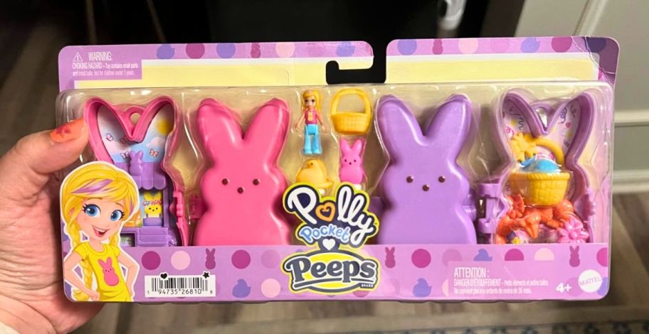 a womans hand holding a packaged polly pocket peeps play set