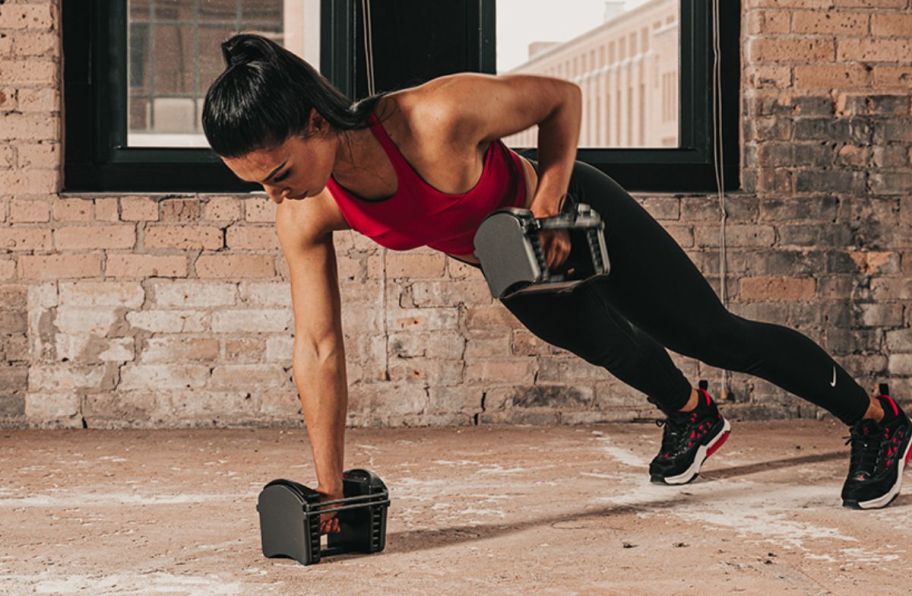 a woman in workout gear using a set of expandable dumbbells