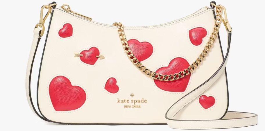 a small white crossbody bag covered in red puffy hearts