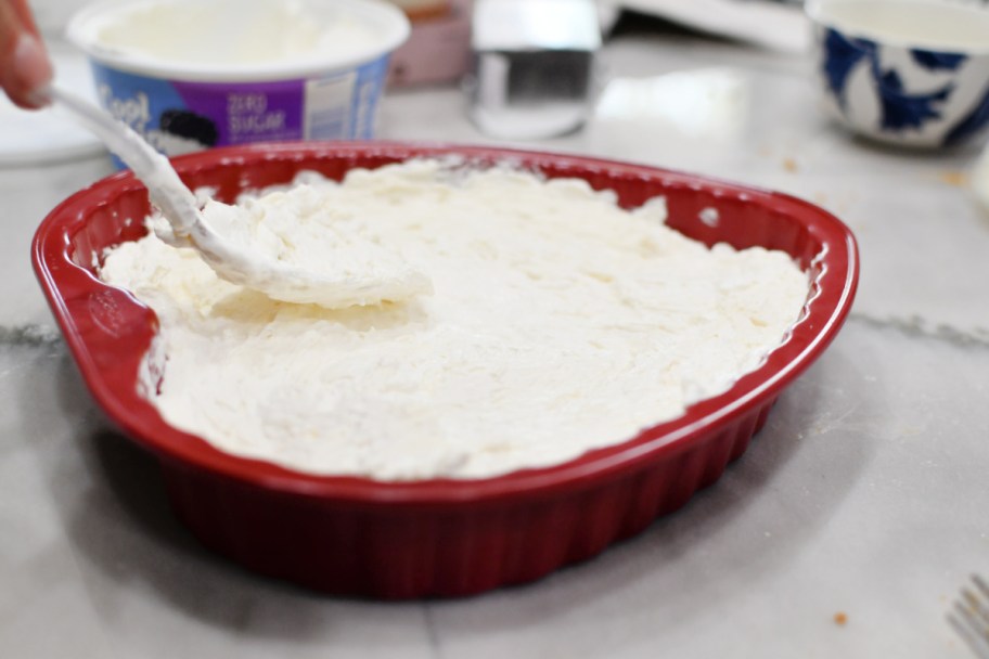 spreading cream cheese cherry delight on a pie plate 