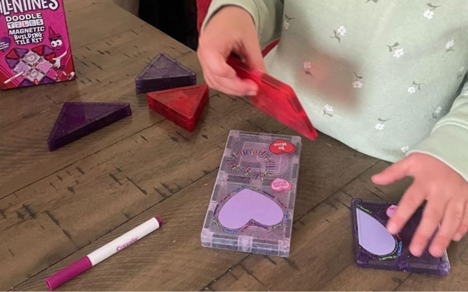 a little kid playing with a valentines magnetic tile set