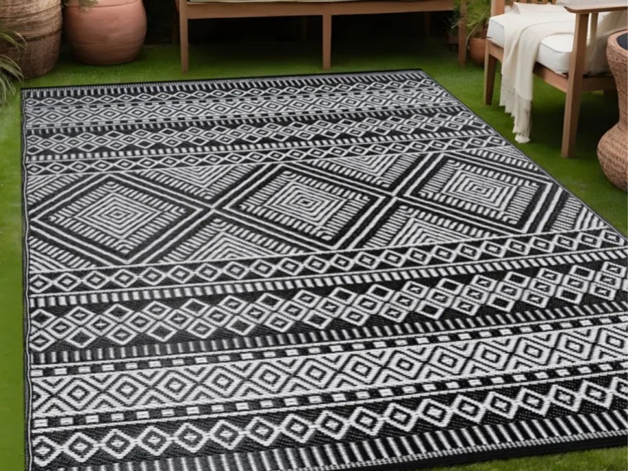 a large black and white moraccan print outdoor rug on a patio