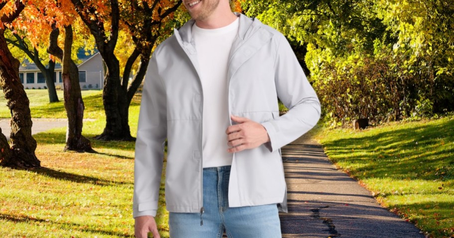 man wearing a grey raincoat, standing outside