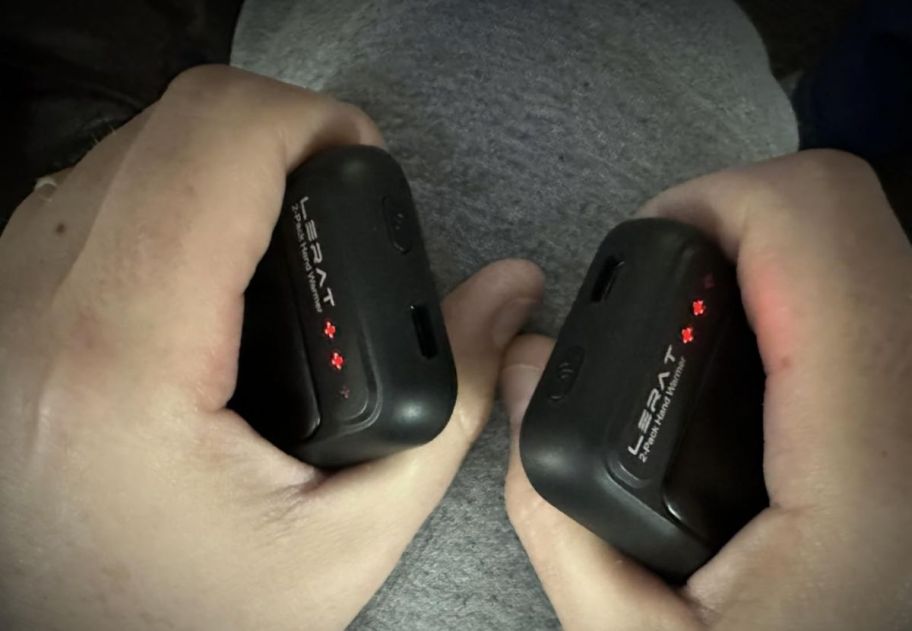 a persons hands each holding a rechargeable hand warmer