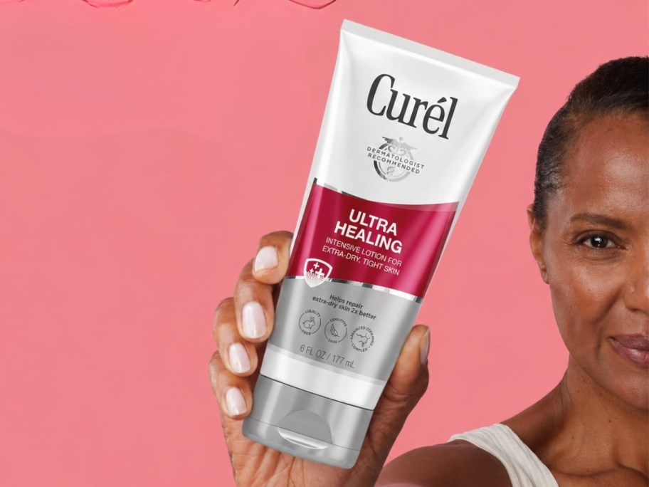 woman holding bottle of curel ultra intensive lotion with pink background